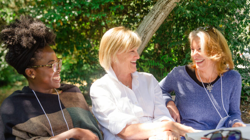 Three women sit together outside