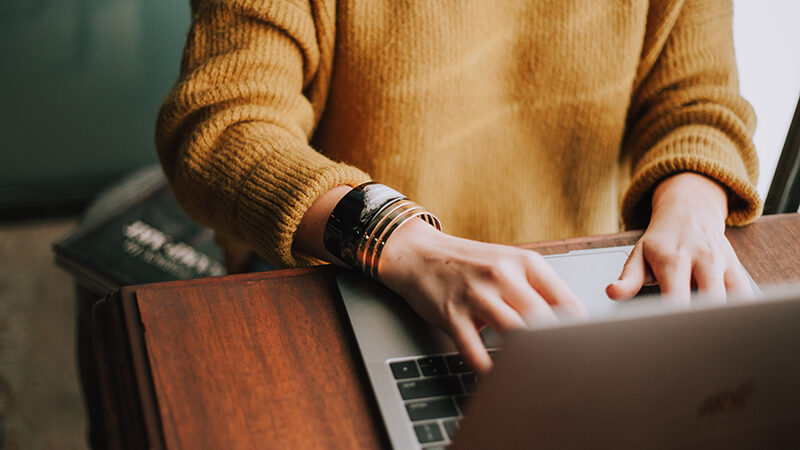 A person in a yellow sweater using a computer